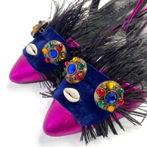 Close-up of jeweled embellishment, cowrie, and feather work